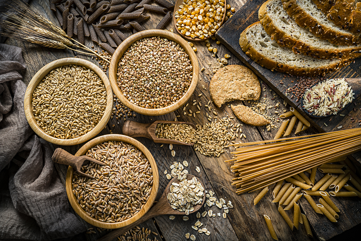 Top view of wholegrain and cereal composition shot on rustic wooden table. This type of food is rich of fiber and is ideal for dieting. The composition includes wholegrain sliced bread, various kinds of wholegrain pasta, wholegrain crackers, grissini, oat flakes, brown rice, spelt and flax seeds. Predominant color is brown. High resolution 42Mp studio digital capture taken with SONY A7rII and Zeiss Batis 40mm F2.0 CF lens