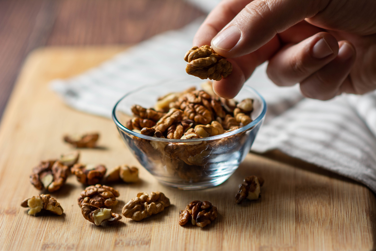 Selective focus. Male hands extract a walnut from the shell. Walnuts bowl. close-up of a hand with walnuts